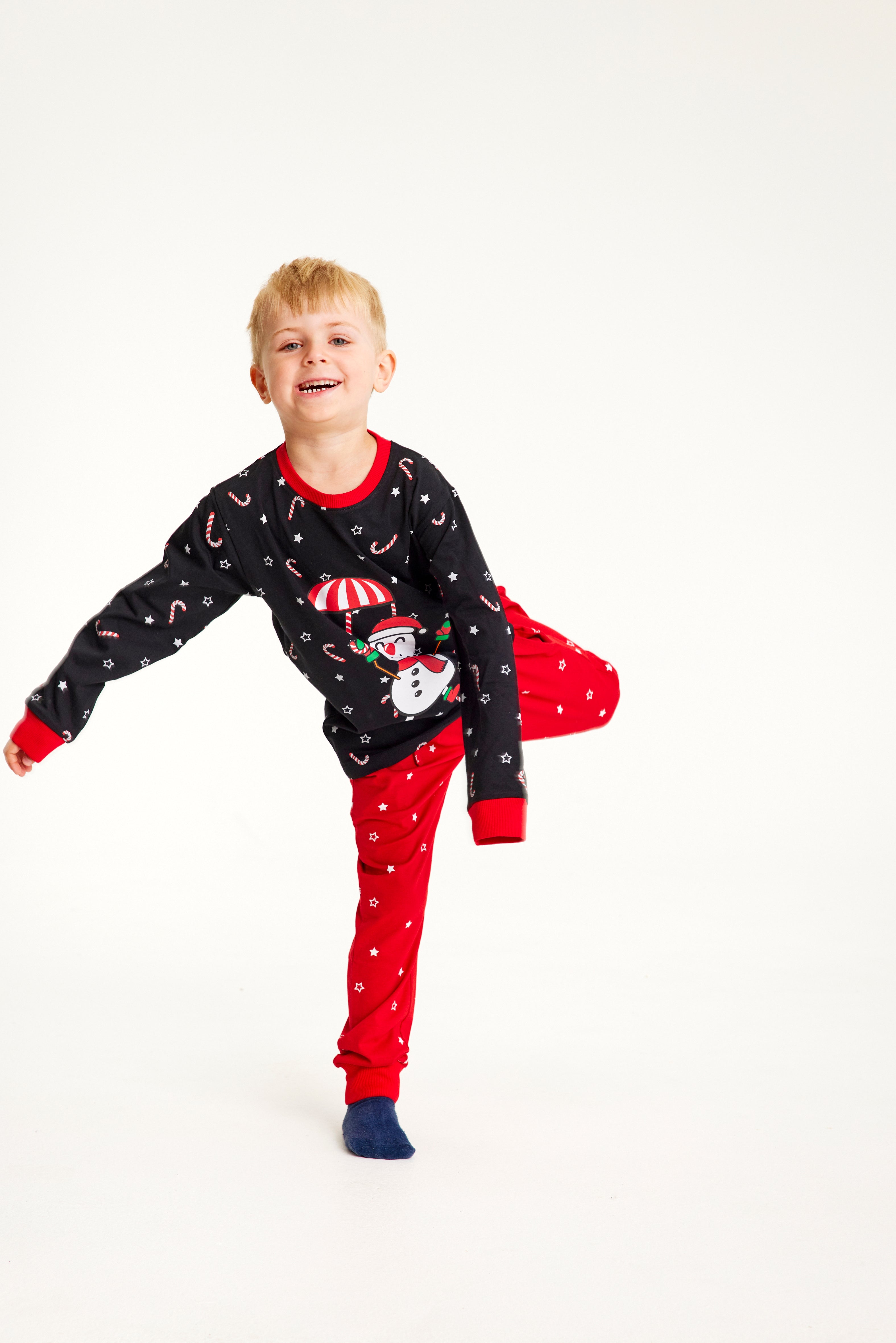 Schwarzer Weihnachtspullover mit fliegendem Schneemann und rote Weihnachtspyjamahose mit weißen Sternen für Kinder.